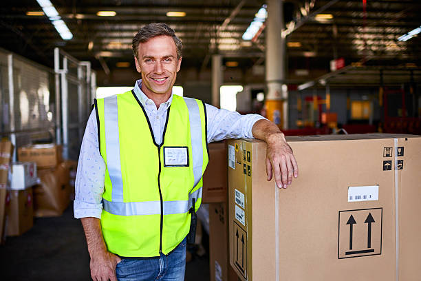 portrait of a warehouse worker standing next to boxes in a large warehouse